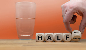 A glass filled halfway next to blocks spelling 'HALF' with the option to show 'full' or 'empty,' symbolizing perspective and optimism versus pessimism
