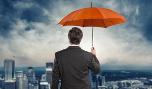 Man holding an orange umbrella overlooking a city